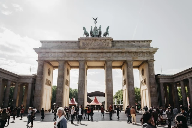 Crowds gather in front of the Brandenburg Gate in Berlin on a bright day